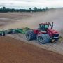 A red Case IH tractor pulling a K-Line Ag Speedtiller incorporating lime into a ploughed paddock