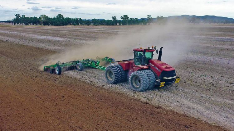 A red Case IH tractor pulling a K-Line Ag Speedtiller incorporating lime into a ploughed paddock