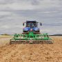 A K-Line Ag SpeedChisel machine being towed through a paddock by a blue tractor